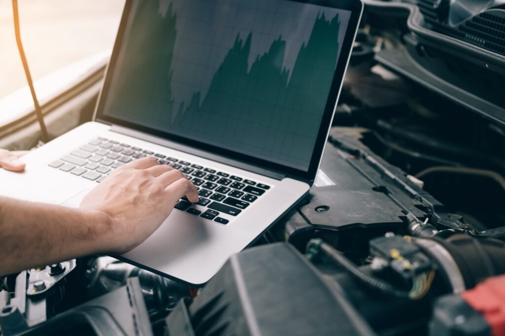 Car repair technicians use laptop computers to measure engine values for analysis.